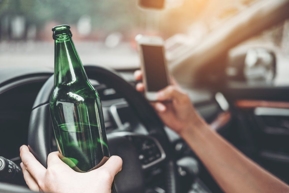 car driver holding phone and liquor drink